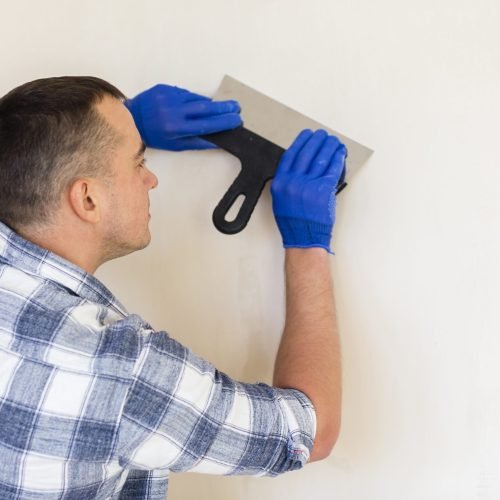 man-holding-trowel-while-working-wall